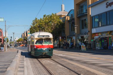 San Francisco caddesinde yeşil ve krem renkli ikonik tramvay, 1077 numara, dükkanlar, modern binalar, sakin atmosfer, turist dostu bölge..