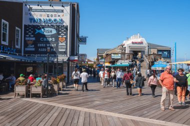 San Francisco 39 numaralı iskelede hareketli bir sahne. Tahta kalaslar ziyaretçilere dükkanlarda, restoranlarda ve eğlencelerde rehberlik eder. Güneşli bir gün, neşeli bir atmosfer, deniz kıyısında sakin bir hava..