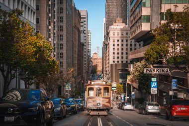San Francisco 'nun mükemmel bir manzarası, kalabalık caddede uzun binaları olan ikonik teleferik. Eski ve yeni mimarinin karışımı, şehir trafiği, yeşillik.
