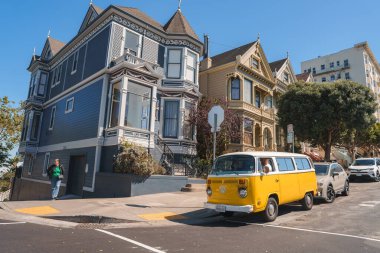 Explore the iconic architecture and steep inclines of San Francisco with a picturesque street scene showcasing Victorian houses, a VW Bus, and modern city life. clipart