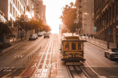 Quintessential San Francisco scene iconic cable car navigating hilly streets in warm sunlight, classic architecture, city vibe, Fishermans Wharf charm. clipart