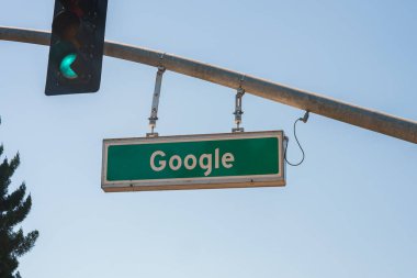 Google ile sokak işareti Google genel merkezi veya ofis, ABD tarzını andırıyor, beyaz harfli yeşil işaret, arka planda açık gökyüzü, trafik sinyali yeşil ışık.