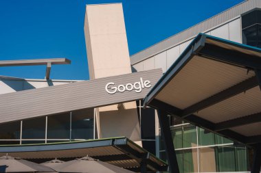 Çağdaş mimari, Google logosu ile gösterişli bir bina cephesi. Temiz çizgiler, geometrik şekiller ve şemsiyeli açık alan. Konum muhtemelen Kaliforniya Dağ Manzarası 'nda.