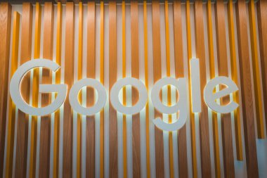 İkonik Google logosunu şık ahşap bir arka planda ışık ve koyu ahşap gölgeli bir şekilde izleyin. Yumuşak ışıkla geliştirilmiş, modern ve sıcak bir atmosfer yaratıyor..