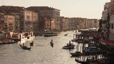 Venedikli gondolcu Venedik İtalya 'nın yeşil kanal sularında gondola biniyor. Ünlü Canal Grande 'deki geleneksel Gondol manzarası gün batımında romantik altın bir akşam ışığı altında.