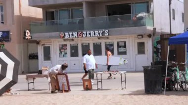 Venice plaj bölgesindeki palmiye ağaçları ve binaların oradaki insanlar. Venedik plaj ruhu. Renkli binalar, tabelalar ve insanlar koşup paten kayıyor..
