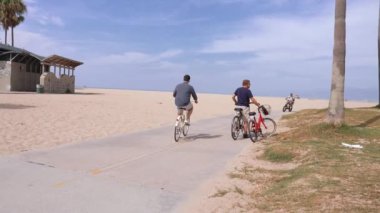 Venice plaj bölgesindeki palmiye ağaçları ve binaların oradaki insanlar. Venedik plaj ruhu. Renkli binalar, tabelalar ve insanlar koşup paten kayıyor..