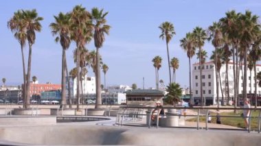 Venice sahilindeki kaykay parkında Pasifik Okyanusu kıyısında kayan insanlar var. Dünyanın en iyi ve en popüler kaykay parkı..