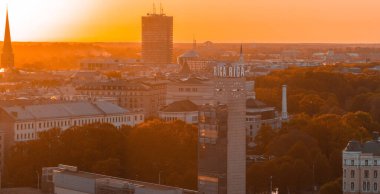 Riga 'nın Letonya' daki eski kasabasında hava panoramik günbatımı. Riga 'da güzel bir bahar günbatımı. Riga saat kulesi tren istasyonunun yakınındaki manzarayı kapat. Altın saat yangın günbatımı.