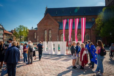 Riga, Letonya 'da güneşli bir gün. Önünde LATVIA harfleri, bayrak renkleri. Tramvay otobüsü, tarihi bina, temiz gökyüzü. AB 'de 20 yılı kutluyoruz.