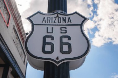 Arizona 'daki Iconic Route 66 tabelasında siyah harflerle ARIZONA ve US 66 yazıyordu. Bulutlu gökyüzü ve kentsel ortam. Büyük ihtimalle Williams 'da, Büyük Kanyon yakınlarında..