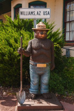 Williams, AZ, ABD 'de gerçek boyutlarda Smokey Bear heykeli. Kürek, kot pantolon, korucu şapkası ve işaret levhası var. 66. Otoyol yakınlarında turist dostu eğlence..
