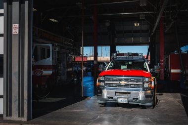 Colorado 'dan gelen kırmızı beyaz Chevrolet kamyonlu itfaiye garajı göreve hazır. Arka planda park etmiş itfaiye arabası var. Şehir ayarları.