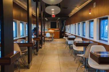 Interior of a Route 66 themed diner in Barstow, USA. Retro white chairs, wood paneling, and warm tones create a nostalgic ambiance for travelers and locals. clipart