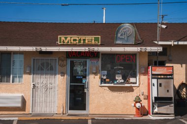 Route 66 'daki Barstow' da klasik bir Amerikan motelini keşfet. Retro neon tabelalar, klasik Coca Cola makinesi ve nostaljik benzin pompası güneşli çöl gökyüzünün altında klasik bir atmosfer yaratır..