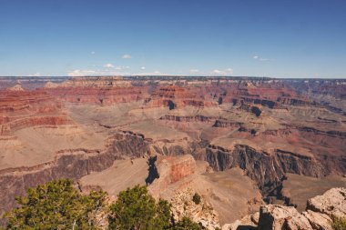 Büyük Kanyon 'un panoramik manzarası, Arizona, ABD. Kızıl kayaların, derin vadilerin, yeşilliklerin ve açık mavi gökyüzünün çarpıcı katmanlarını yakalıyor. Popüler turizm merkezi büyük ölçekli olarak bilinir..