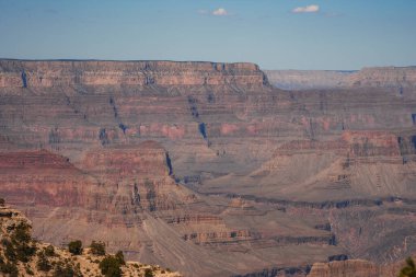 Experience the majestic beauty of the Grand Canyon in Arizona, USA. The photograph showcases stunning layers of red, brown, and gray rock formations under a clear blue sky. clipart