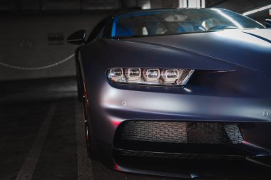 Pürüzsüz, modern Bugatti Chiron ve mat kaplama. Yüksek performans tasarımı, LED farlar, kapalı bir yere park edilmiş, loş ışıklandırmalı, muhtemelen Los Angeles 'ın zengin bir bölgesinde..