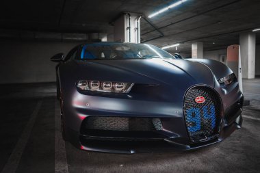 Loş yeraltı otoparkında loş ışıklı Bugatti Chiron. Parlak, koyu renk bir vücut, LED farlar, yüksek kalite tasarım. Muhtemelen Los Angeles 'ta..