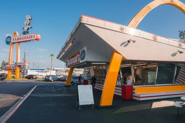 Vintage McDonalds restaurant in Los Angeles with iconic golden arches, retro design, and classic HAMBURGERS sign. Americana captured in historic landmark setting. clipart