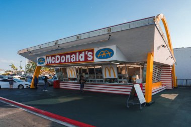 McDonalds restoranı eski Amerikan lokantası tarzında. Beyaz cephe, kırmızı ve sarı çizgiler, altın kemer logosu. Mekan Los Angeles olabilir, güneşli bir gün..