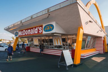 Los Angeles 'ta klasik Amerikan lokantası tarzı McDonalds, 1950' leri hatırlatıyor. İkonik altın kemerler, kırmızı ve beyaz tasarım, güneşli bir günde gezen müşteriler..