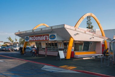 Los Angeles 'taki ayırt edici McDonalds restoranı. Altın kemerlere benzeyen eşsiz bir mimari tasarımı var. Retro titreşim, açık gökyüzü, sıradan insanlar, arka planda palmiye ağaçları..