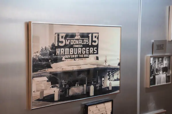 stock image Vintage black and white photograph of early McDonalds location with iconic architecture and 15 cent hamburger price, likely displayed in Los Angeles museum.