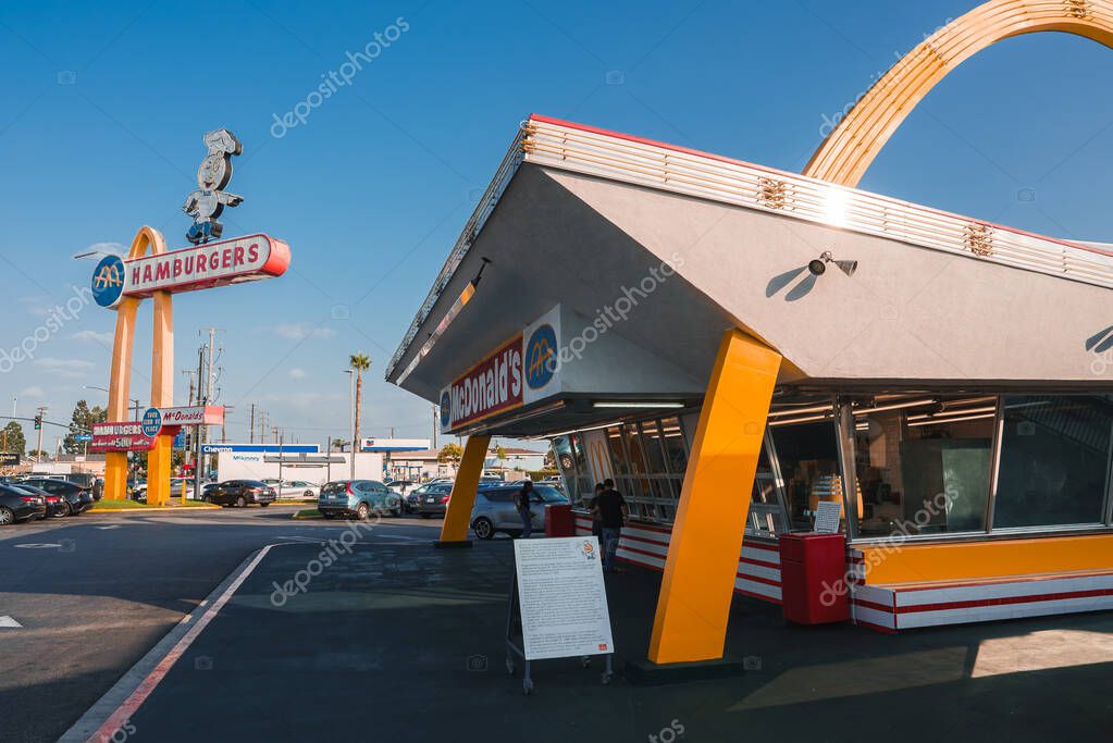 Iconic fast food restaurant with retro futuristic 1950s or 60s American diner style in Los Angeles. Vibrant colors, playful signage, sunny day atmosphere.