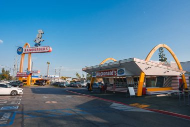 Eski tasarımı olan ikonik McDonalds, altın kemerler, HAMBURGERS işareti, klasik şef karakteri. 1950 'lerin tarzına benziyor. Yoğun bir yer, muhtemelen Los Angeles..
