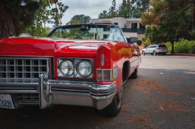 1970 'lerden kalma üstü açık kırmızı bir araba bir yerleşim yerine park edilmiş. Krom detaylı klasik Amerikan tasarımı. Muhtemelen Los Angeles 'ta..