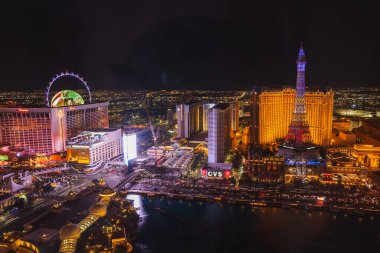Vibrant night view of the Las Vegas Strip with iconic illuminated skyline, Eiffel Tower replica, and High Roller observation wheel. Exciting and entertaining scene full of lights. clipart