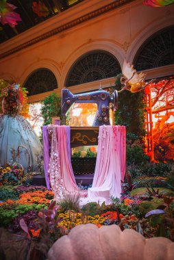 Renkli çiçekler ve yemyeşil yapraklarla çevrili klasik dikiş makinesi süsüsüyle dolu canlı bir bahçe sahnesi. Las Vegas 'ın varlıklı ve teatral özünü yakalar.