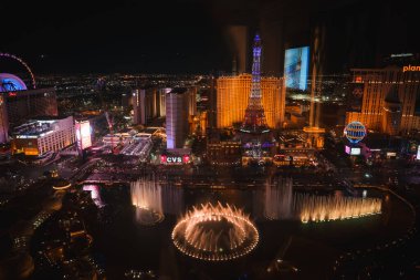 Vibrant Las Vegas Strip night scene with Bellagio fountains lit up and shooting water high, Eiffel Tower replica, glowing lights, and lively atmosphere. clipart