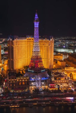 Nighttime view of the Las Vegas Strip featuring the illuminated Eiffel Tower replica at Paris Las Vegas Hotel. City lights showcase vibrant nightlife. clipart