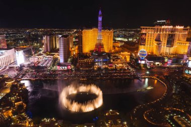 A vibrant aerial view of the Las Vegas Strip at night, featuring iconic buildings and attractions like Bellagio fountains, Eiffel Tower replica, Planet Hollywood, and bustling city lights. clipart