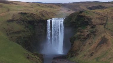 Gün batımında İzlanda 'nın etkileyici güzellikte doğası. Skogafoss şelalesi İzlanda 'nın ünlü bir doğal dönüm noktasıdır. Turistler ünlü şelale yakınlarında ata binerler..