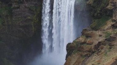 Gün batımında İzlanda 'nın etkileyici güzellikte doğası. Skogafoss şelalesi İzlanda 'nın ünlü bir doğal dönüm noktasıdır. Turistler ünlü şelale yakınlarında ata binerler..