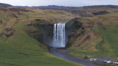 Gün batımında İzlanda 'nın etkileyici güzellikte doğası. Skogafoss şelalesi İzlanda 'nın ünlü bir doğal dönüm noktasıdır. Turistler ünlü şelale yakınlarında ata binerler..