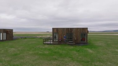 İzlanda 'da, arka planda rahat pansiyonları ve dağları olan iki arkadaşın hava manzarası. Issız bir yerde ahşap bir kulübe.. 