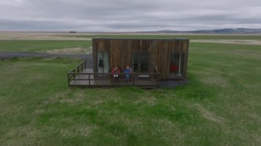 İzlanda 'da, arka planda rahat pansiyonları ve dağları olan iki arkadaşın hava manzarası. Issız bir yerde ahşap bir kulübe.. 