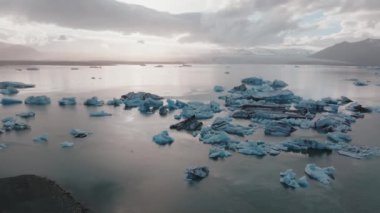 İzlanda 'daki Jokulsarlon buzulunda eriyen zümrüt turkuaz mavisi buzdağlarıyla güzel bir gün batımı..