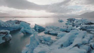 İzlanda 'daki Jokulsarlon buzulunda eriyen zümrüt turkuaz mavisi buzdağlarıyla güzel bir gün batımı..