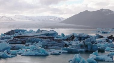 İzlanda 'daki Jokulsarlon buzulunda eriyen zümrüt turkuaz mavisi buzdağlarıyla güzel bir gün batımı..