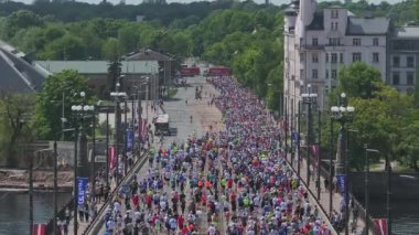 Riga Rimi Maratonu 2024. Maraton etkinliği sırasında şehirde koşan kalabalığın hava görüntüsü. Toprak setten başlayın ve insanlar Daugava nehrinden şehir merkezine doğru koşun..