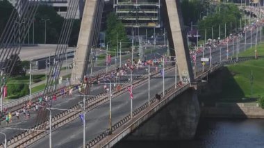 Riga Rimi Maratonu 2024. Maraton etkinliği sırasında şehirde koşan kalabalığın hava görüntüsü. Toprak setten başlayın ve insanlar Daugava nehrinden şehir merkezine doğru koşun..
