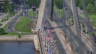 Riga Rimi Maratonu 2024. Maraton etkinliği sırasında şehirde koşan kalabalığın hava görüntüsü. Toprak setten başlayın ve insanlar Daugava nehrinden şehir merkezine doğru koşun..