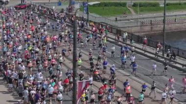 Riga Rimi Maratonu 2024. Maraton etkinliği sırasında şehirde koşan kalabalığın hava görüntüsü. Toprak setten başlayın ve insanlar Daugava nehrinden şehir merkezine doğru koşun..