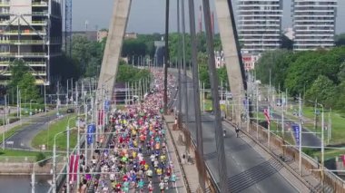 Riga Rimi Maratonu 2024. Maraton etkinliği sırasında şehirde koşan kalabalığın hava görüntüsü. Toprak setten başlayın ve insanlar Daugava nehrinden şehir merkezine doğru koşun..