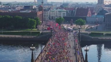 Riga Rimi Maratonu 2024. Maraton etkinliği sırasında şehirde koşan kalabalığın hava görüntüsü. Toprak setten başlayın ve insanlar Daugava nehrinden şehir merkezine doğru koşun..
